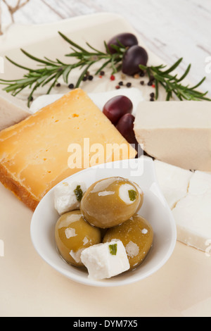 Luxuriöse Oliven und Käse Hintergrund. Grüne Oliven und verschiedenen Käsesorten, Rosmarin und Pfefferkörner im hellen vintage Stockfoto