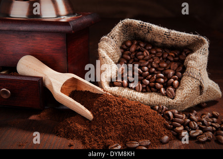 Traditionellen Kaffee Stillleben. Gemahlener Kaffee, Kaffeebohnen, Kaffeemühle, Holzlöffel mit Kaffee und Tasche mit Kaffeebohnen Stockfoto
