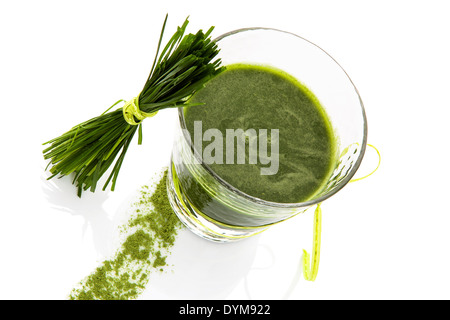 Grüne Supernahrungsmittel. Grüner Saft im Glas und Weizen Grass auf grünem Hintergrund isoliert. Gesundes Wohnen. Stockfoto