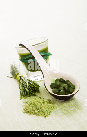 Weizengras, Gerstengras, Chlorella, Spirulina. Pflanzliche, natürliche Nahrungsergänzungsmittel. Gemahlenem Pulver, Pillen auf Löffel und grünen Saft. Stockfoto