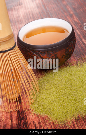 Traditionelle pulverisierter Grüntee Matcha auf hölzernen Hintergrund mit Bambus Chasen und eine Tasse Tee. Teetrinken. Stockfoto
