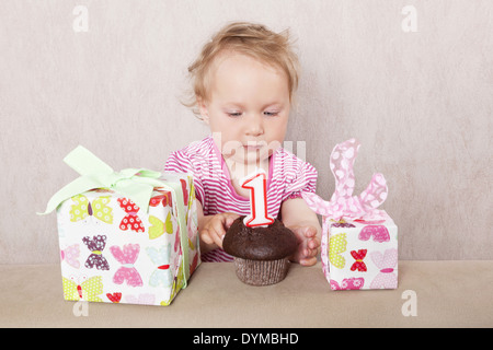 Ersten Geburtstag. Charmante kaukasische Mädchen mit Geschenken und Geburtstagskuchen auf beigen Hintergrund. Stockfoto