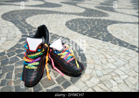 Viel Glück Fußballschuhe Fußball geschnürte mit brasilianischen Wunsch Bändern auf dem Bürgersteig Copacabana Strand Rio De Janeiro Fußball-Stollen Stockfoto