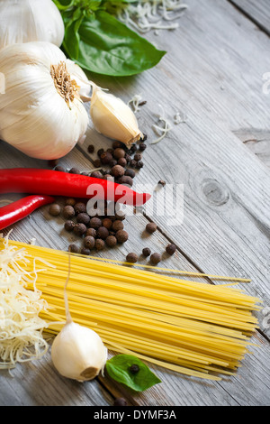 Traditionelle Zutaten der italischen Küche - Knoblauch, Paprika, Basilikum und gemaserte Parmigiano. Selektiven Fokus. Stockfoto