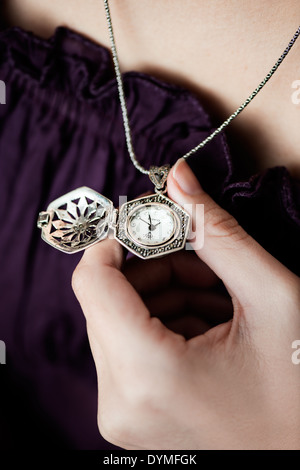 Frau auf lila Kleid mit einem Anhänger auf ihre Hand. Stockfoto