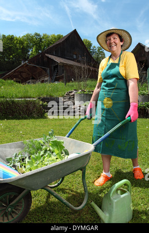 Foto einer pensionierten Frau in ihrem 60 ist ihre neue Pflanzen in ihrem Garten mit einer Schubkarre bewegen. Stockfoto