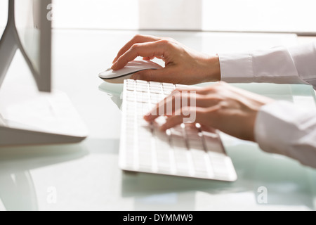 Frau mit einer Maus und Tastatur Computer am Schreibtisch Stockfoto