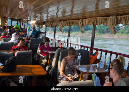 Horizontale Ansicht von westlichen Touristen, die Reisen auf dem Mekong Fluss in einem laotischen langsamen Boot. Stockfoto