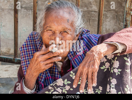 Alte Dame raucht eine Zigarre drausen einen Tempel in Mandalay Stockfoto