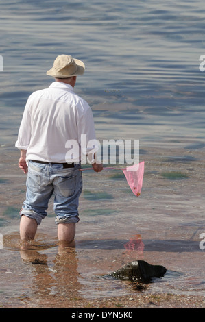 Mann, Paddeln im Meer mit Kindes Fischernetz. Stockfoto