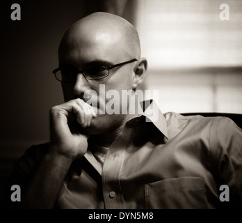 Glatzköpfiger Mann mit Brille vor Fenster denken Stockfoto