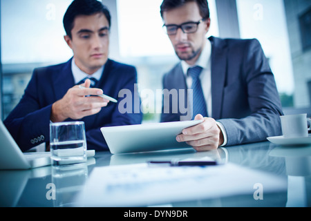 Bild von Business Objects und zwei Jungunternehmer Dokument im Touchpad Tagung diskutieren Stockfoto
