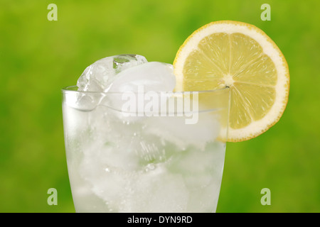 Kaltes Wasser in ein Glas mit Eiswürfeln, mit einer Zitronenscheibe serviert Stockfoto