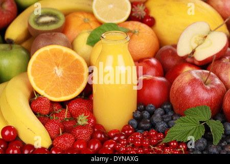Orangensaft in einer Flasche, umgeben von frischen Früchten Stockfoto