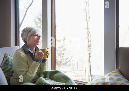 Ältere Frau, die Tasse Kaffee auf sofa Stockfoto