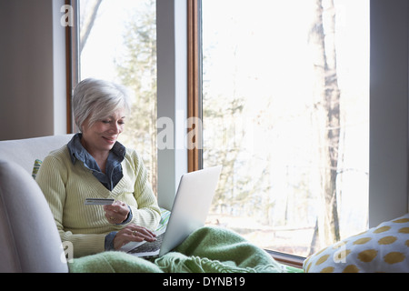 Ältere Frau, Online-shopping auf sofa Stockfoto