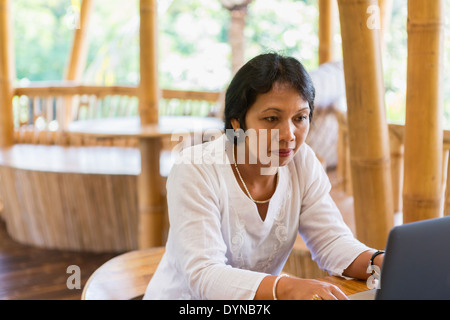 Balinesische Frau mit Laptop am Tisch Stockfoto