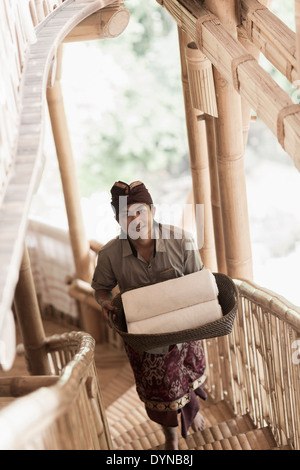 Balinesische Mann trägt gerollt Handtücher im Hotel, Ubud, Bali, Indonesien Stockfoto