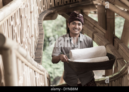 Balinesische Mann trägt gerollt Handtücher im Hotel, Ubud, Bali, Indonesien Stockfoto