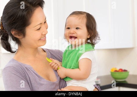 Mutter mit Babymädchen in Küche Stockfoto