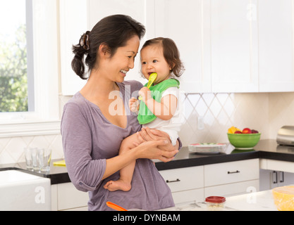 Mutter mit Babymädchen in Küche Stockfoto