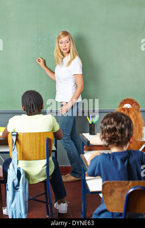 Lehrer schreibt an die Tafel im Matheunterricht in der Grundschule Stockfoto