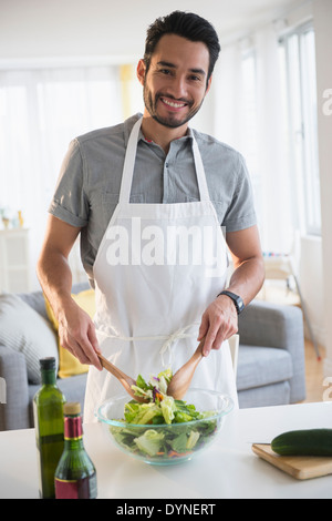 Gemischte Rassen Mann warf Salat am Tisch Stockfoto