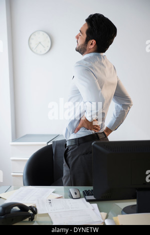Gemischte Rassen Geschäftsmann rieb seinen Rücken im Büro Stockfoto