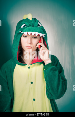 Schwere Frau in Dinosaurier Kostüm halten Handys Stockfoto