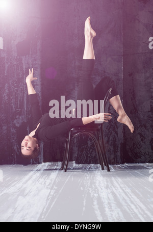 Frau, die Durchführung von akrobatischen Pose auf Stuhl Stockfoto