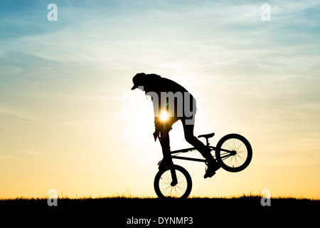 Young Man Tricks auf seinem BMX-Rad zu machen. Silhouette Stockfoto