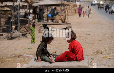 ISLAMABAD, PAKISTAN-APRIL 23: Afghanische Flüchtlinge, die Kinder spielen, während andere in der Slum-Gegend in der Nähe von Islamabad, Pakistan gehen. Mehr als fünf Millionen afghanischen Flüchtlinge flohen ihre Heimat seit sowjetischen Invasion der 1970er Jahre. Rund 3,6 Millionen afghanischen Flüchtlinge haben nach Afghanistan aus Pakistan seit März 2002 unter ein Dreierabkommen zwischen UN Refugee Agency (UNHCR) und die Regierungen von Pakistan und Afghanistan zurückgeführt worden. Mehr als 1,6 Millionen afghanischen Flüchtlinge sind noch in Pakistan, insbesondere in Lagern und Slums Leben und nicht zurück in ihre Heimat aufgrund weiterhin Stockfoto