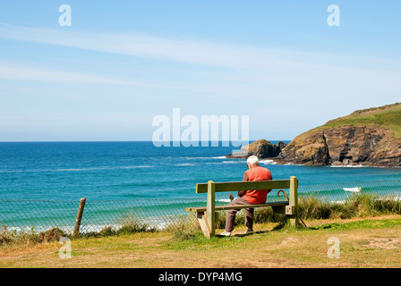 ein älterer Mann sitzt auf einer Bank mit Blick auf das Meer Stockfoto