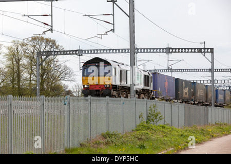 Ein Güterzug schleppt containerisierte Ware entlang der West Coast Main Line in den Midlands. Stockfoto