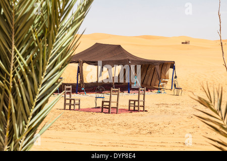 Open Side Zelt und Stühle mit Palmen im Vordergrund unter den Sanddünen am Erg Chebbi Wüste Sahara, Marokko, Nordafrika Stockfoto