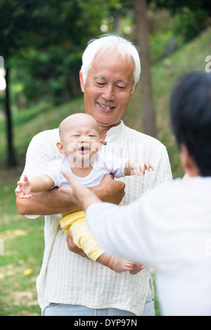 asiatische Baby weint während getröstet von Großeltern Stockfoto