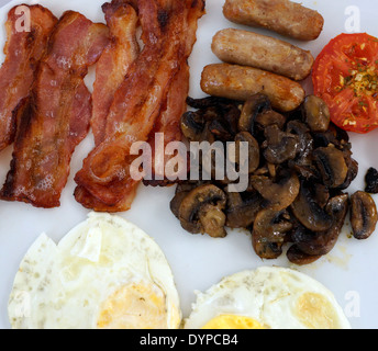 Frühstück mit Spiegeleiern, Speck, Champignons, Tomaten und Würstchen. Stockfoto