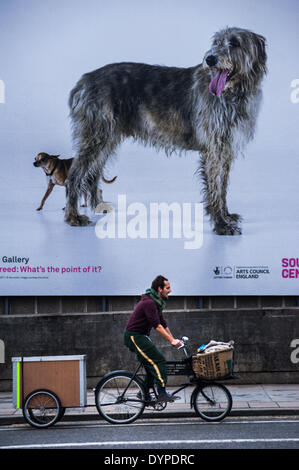 London, UK. 24. April 2014.  ein Mann Zyklen vor einem Plakat auf Waterloo Bridge zur Förderung der neuen Ausstellung von Martin Creed "Was ist der Punkt von ihm?" bei der Hayward Gallery Credit: Piero Cruciatti/Alamy Live News Stockfoto