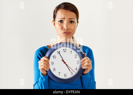 Porträt von asiatischen Geschäftsfrau hält große blaue Armbanduhr und Blick in die Kamera mit Sorge Ausdruck Stockfoto