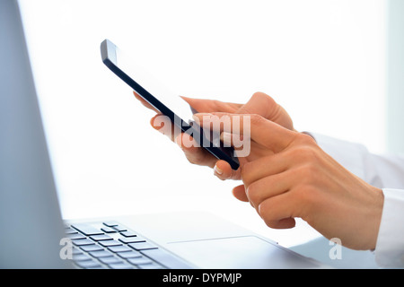 Geschäftsfrau, die Nachricht auf dem Handy im Büro zu schreiben. Stockfoto