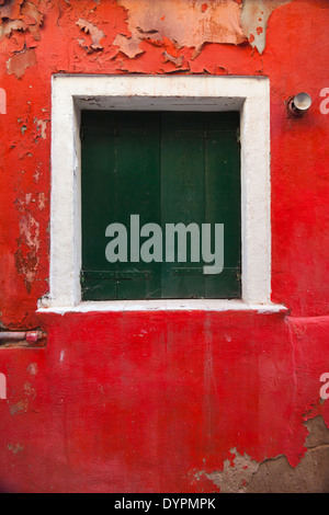 Vertikale Nahaufnahme von Fenster mit grünen Fensterläden auf helle rote Wand, Venedig Stockfoto