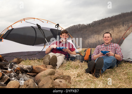 Wanderer beim Abendessen am Feuer auf dem Campingplatz Stockfoto