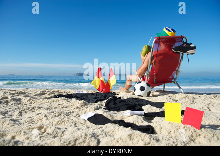 Fußball Fußball-Schiedsrichter eine Pause zum Entspannen im Strandkorb mit Kokosnuss Stockfoto