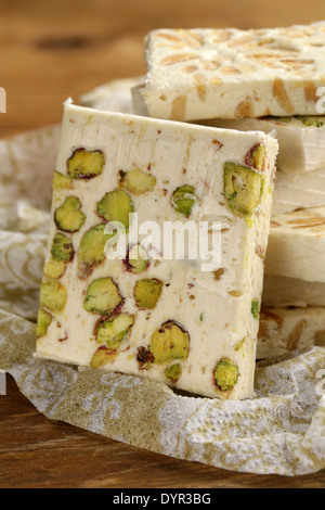 weißer Nougat mit verschiedenen Nüssen auf einem Holztisch Stockfoto