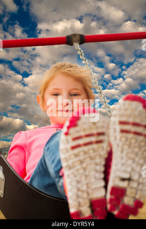 Ein junges Mädchen hat Spaß im Park auf der Schaukel. Stockfoto