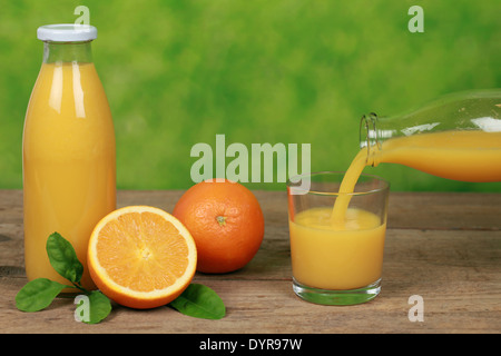 Frischer gepresster Orangensaft ist aus der Flasche in ein Glas gießen. Stockfoto