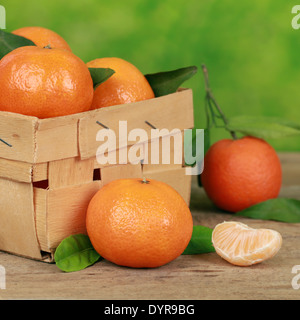 Reife Mandarinen mit Blättern in einer Holzkiste auf einem Tisch Stockfoto