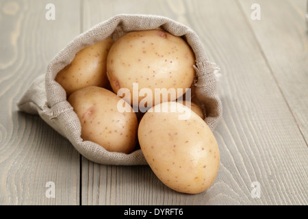 Babykartoffeln in Sackbeutel auf Holztisch Stockfoto