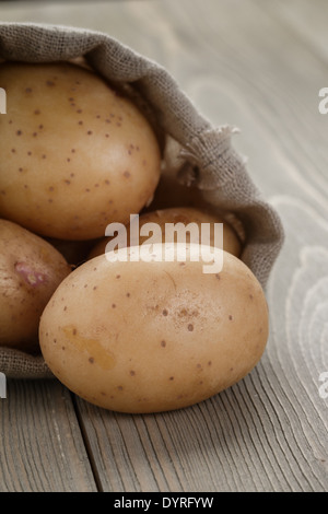 Babykartoffeln in Sackbeutel auf Holztisch Stockfoto