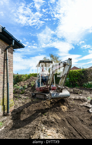 Ein Mikro Kompaktbagger verwendet wird, um einen Rasen Graben vor der Verlegung einer Auffahrt auf eine Wohn home Improvement Projekt Stockfoto